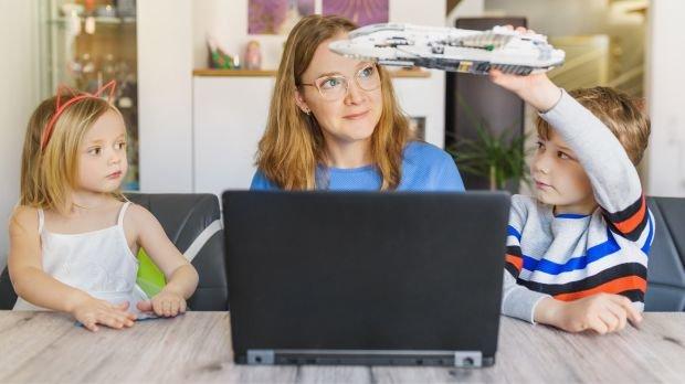 Frau am Laptop mit spielenden Kindern