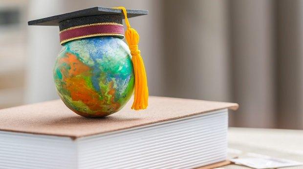 Globus mit Absolventenhut auf Buch